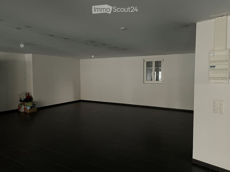 Empty room with dark wooden flooring, white walls, and a single window. No furniture or equipment present.