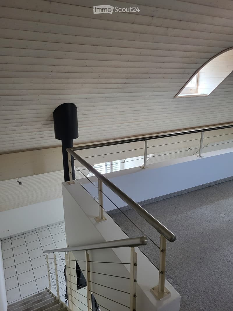 Modern hallway with wooden ceiling, metal railing, and carpeted floor. Features a skylight and a small window at the top.