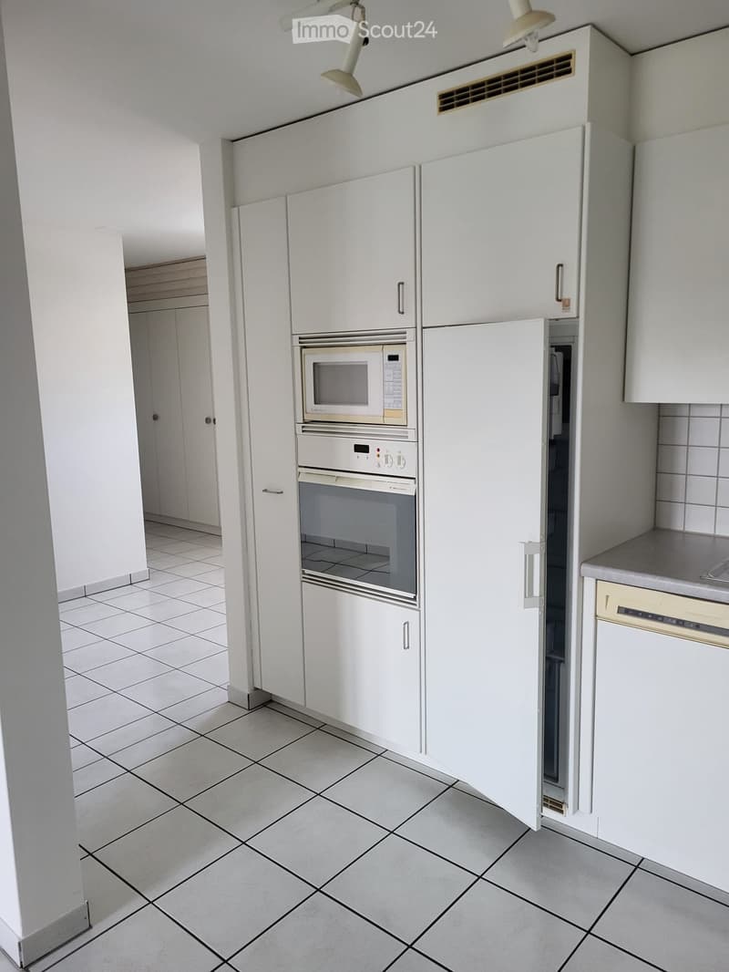 Modern kitchen with white cabinets, tiled floor, microwave, oven, and dishwasher.