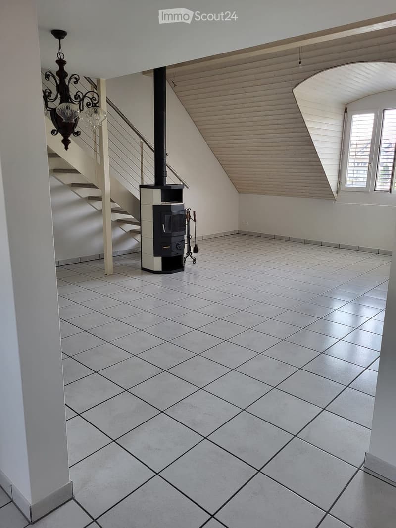 Hallway with tiled floor, staircase, and wood-burning stove with tools nearby.
