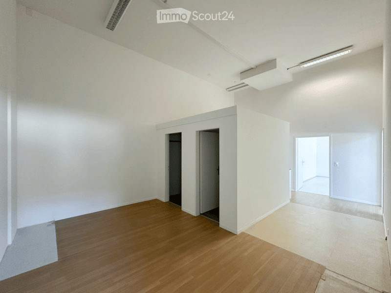 Empty room with white walls, wooden flooring, and several doorways leading to other spaces.