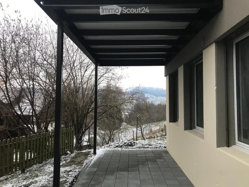 Covered patio with tiled floor, metal roof structure, and scenic view of a snow-covered landscape.