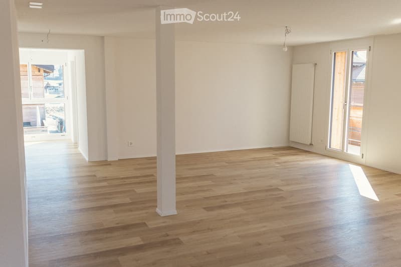 Empty room with light wooden flooring, white walls, and large windows. No furniture or equipment present.