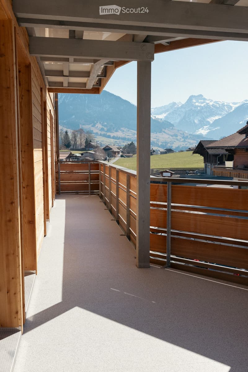 Balcony with wooden railings and a scenic mountain view in the background.