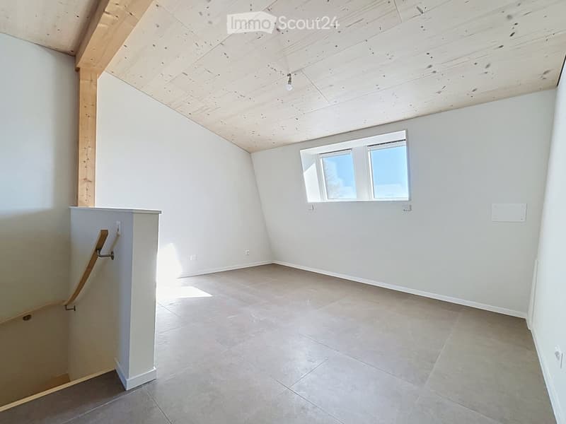 Empty room with white walls, wooden ceiling, tiled floor, and a window with a view. No furniture or equipment is present.