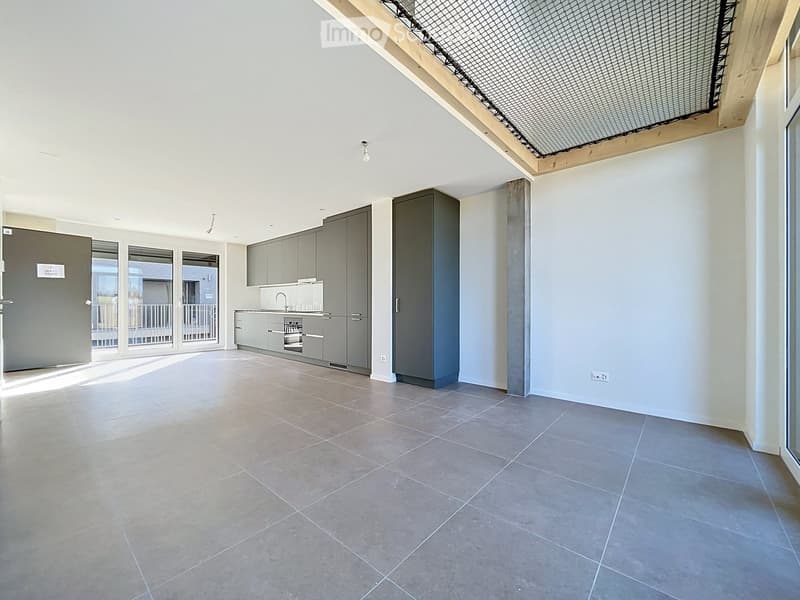 Empty room with tiled floor, grey cabinetry, and large windows leading to a balcony area.