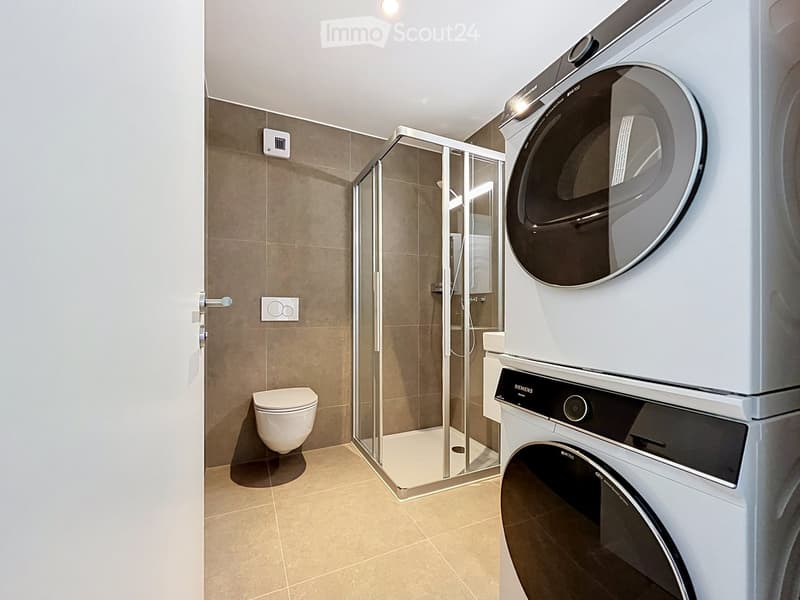 Modern bathroom with a toilet, a glass-enclosed shower, and stacked Siemens washing machine and dryer units.