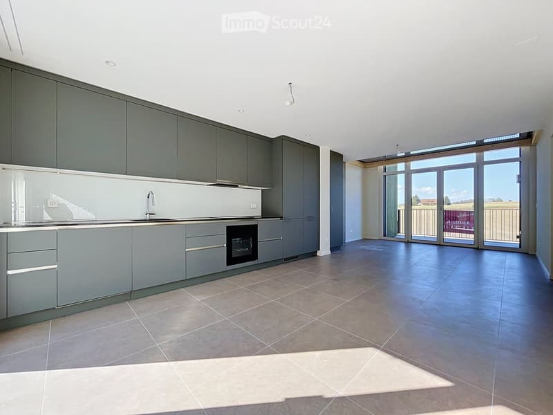 Modern kitchen with grey cabinets, a sink, and an oven, featuring large windows and a tiled floor.