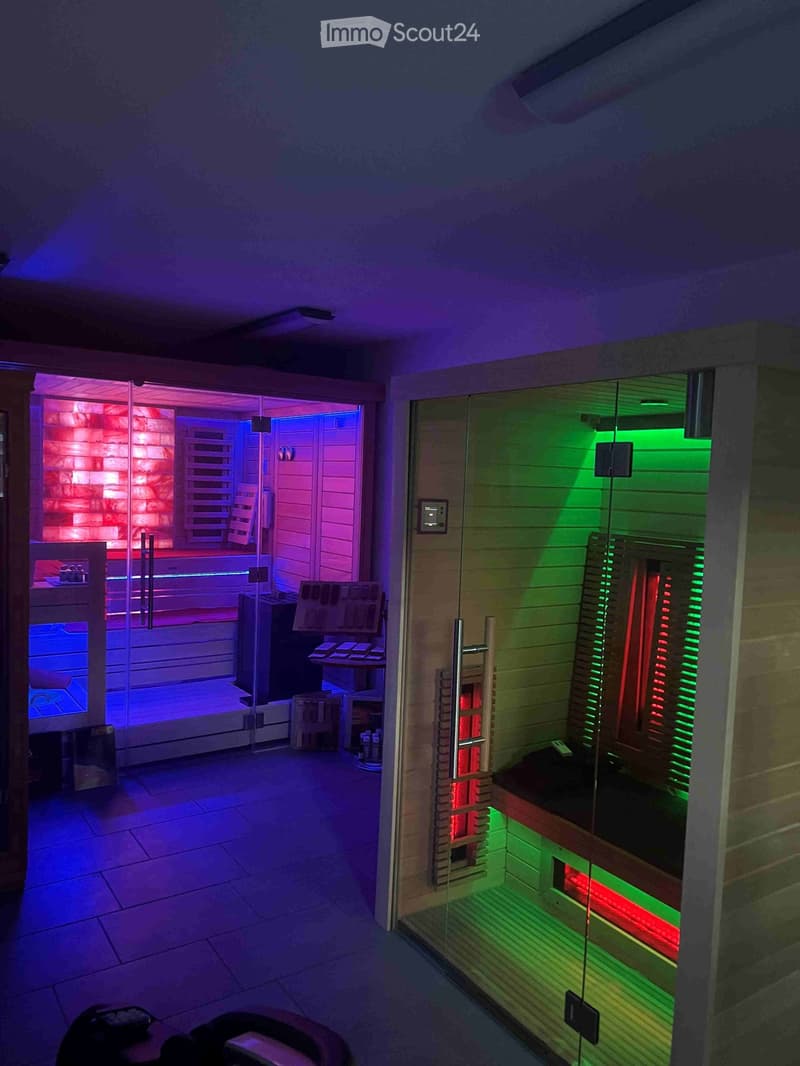 Spa area with a sauna and control panel, featuring wooden benches and colorful lighting.