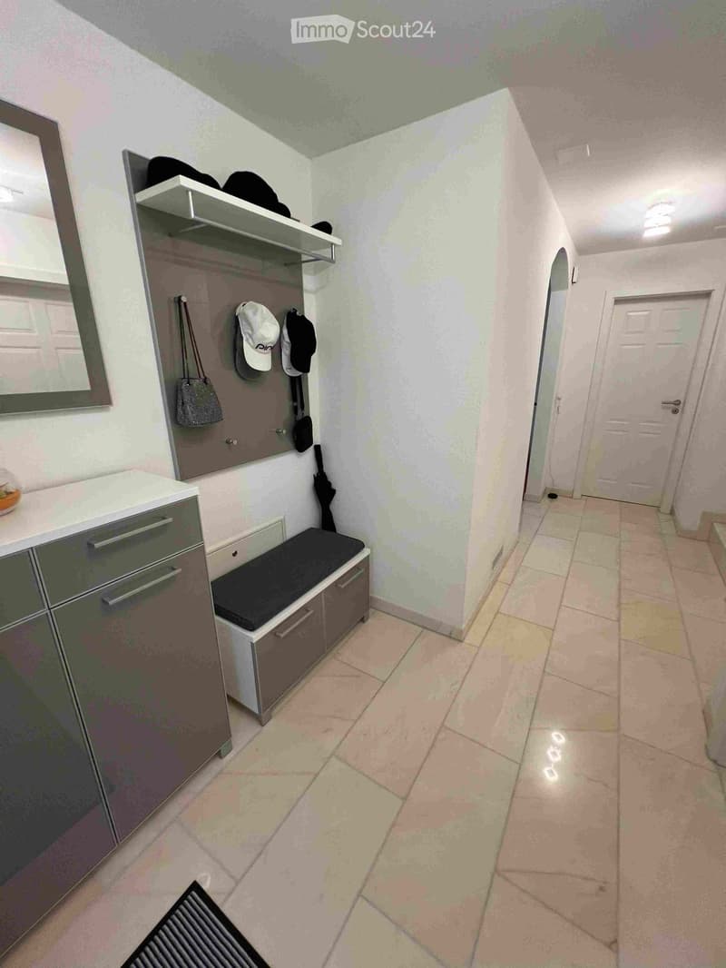 Hallway with tiled floor, storage bench, coat rack, and a small cabinet with a mirror above it.