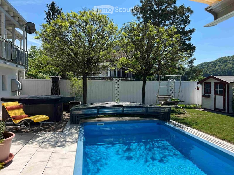 Private outdoor area with a swimming pool, hot tub, lounge chair, swing, and surrounding greenery.