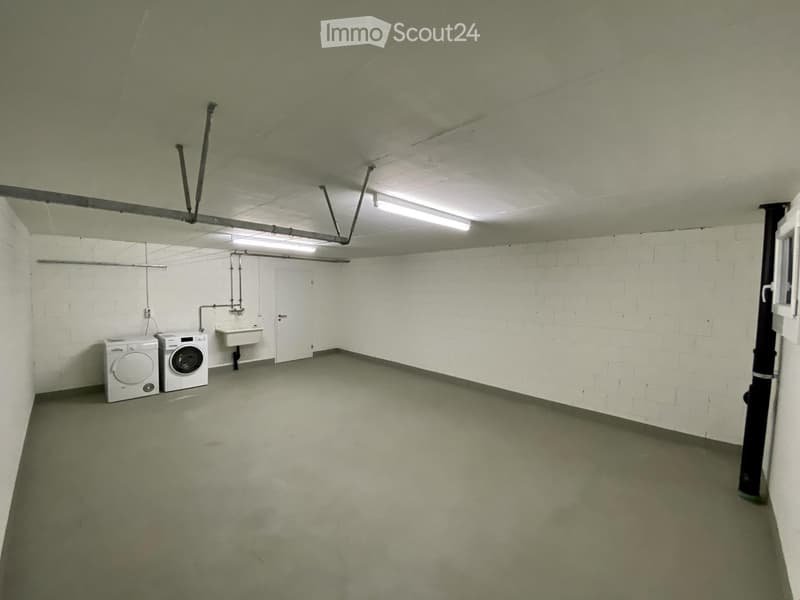 Small utility room with white brick walls, concrete floor, two washing machines, and a sink.