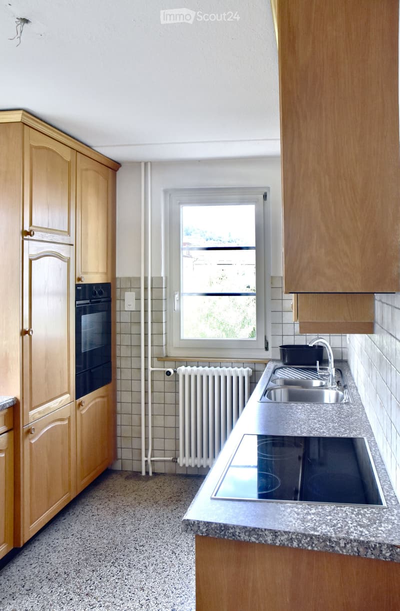Modern kitchen with wooden cabinets, granite countertop, stainless steel sink, and built-in oven.