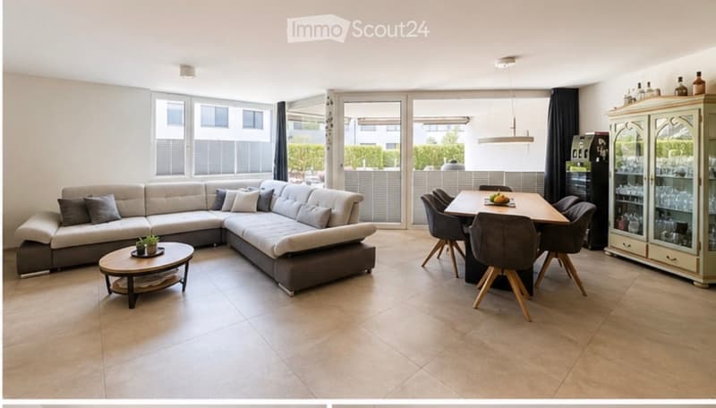 Modern living and dining area with a large L-shaped sofa, coffee table, dining table with chairs, and a cabinet with glass doors.