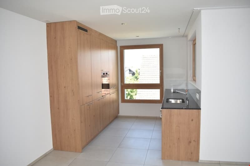 Empty kitchen with wooden cabinets, tiled floor, and a window overlooking a roofed area.