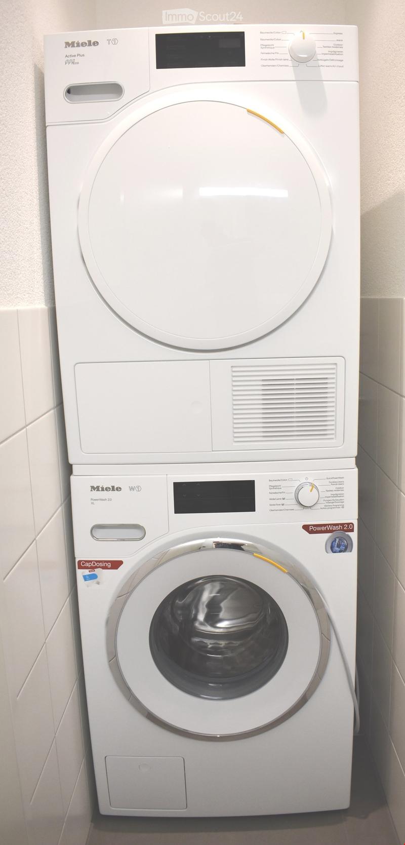 White Miele washing machine and dryer unit with control panels and dials.