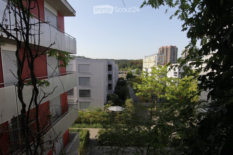 multi-story apartment buildings with balconies, red and white color scheme, green trees and shrubs, paved walkway
