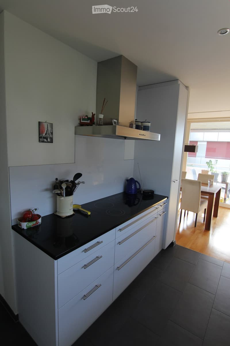 modern kitchen with black countertops, induction cooktop, white cabinets, stainless steel appliances, white dining table