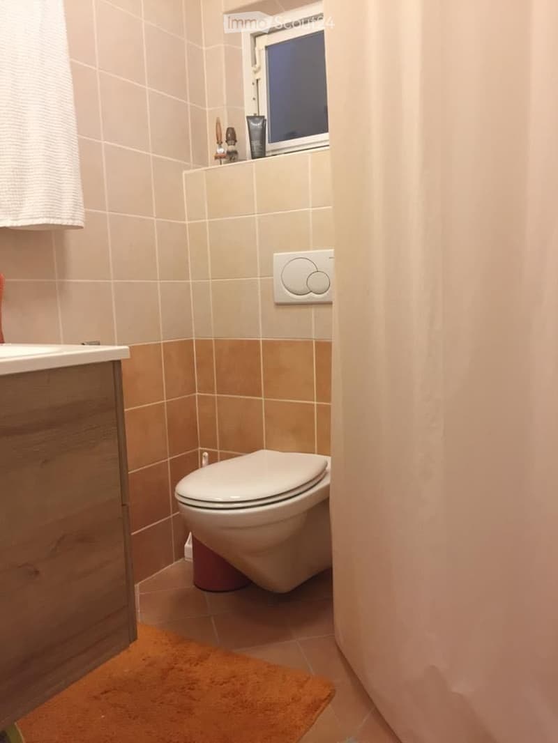 A small bathroom featuring a toilet, a sink, tiled walls, and a shower curtain.