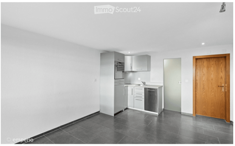 Modern kitchen with grey cabinets, stainless steel appliances, and dark tiled flooring.
