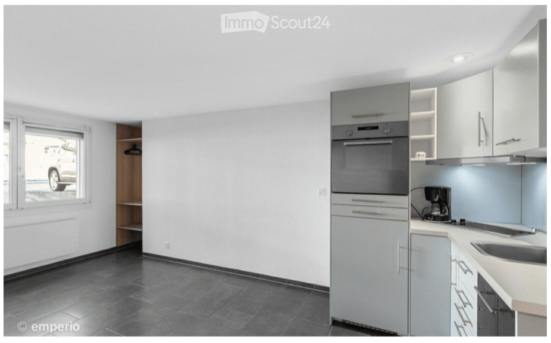 Modern kitchen with white cabinets, stainless steel appliances, and dark tiled flooring.