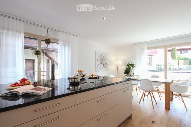 modern kitchen with island, black countertops, white cabinets, dining table, white chairs, large windows, plants