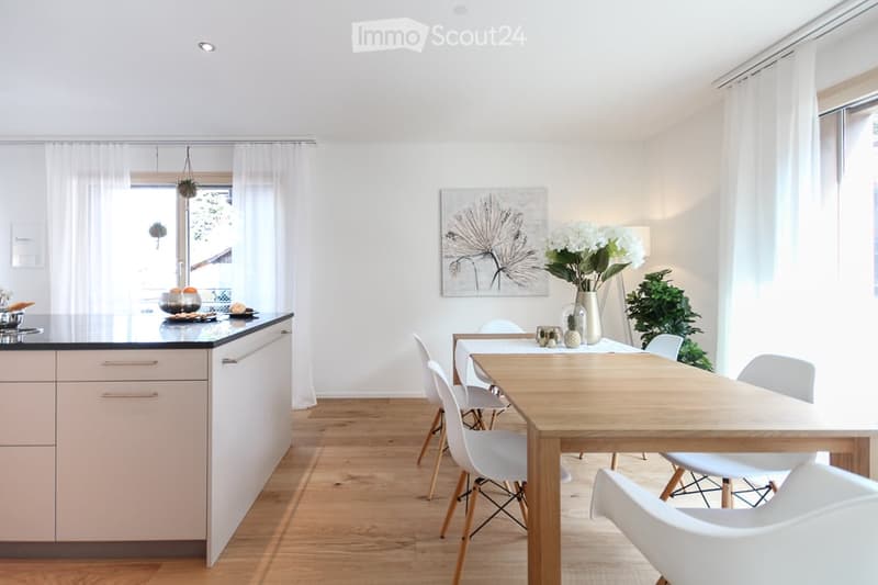 modern kitchen with island, dining table, white chairs, white walls, wooden floor, white curtains, artwork, flowers