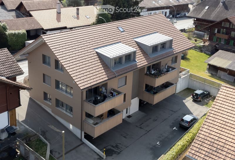 3 story apartment building, brown roof, balconies, parking lot, 2 cars parked