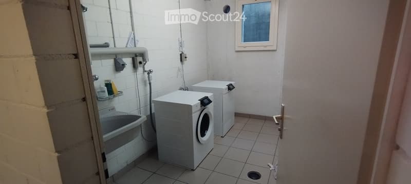 Bathroom with tiled floor and walls, featuring a washing machine, dishwasher, sink, and bathtub.