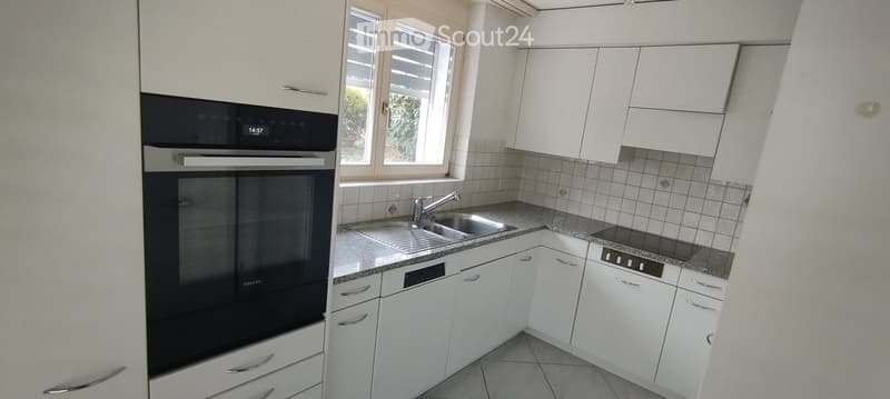 Modern kitchen with white cabinets, stainless steel appliances, and a granite countertop.