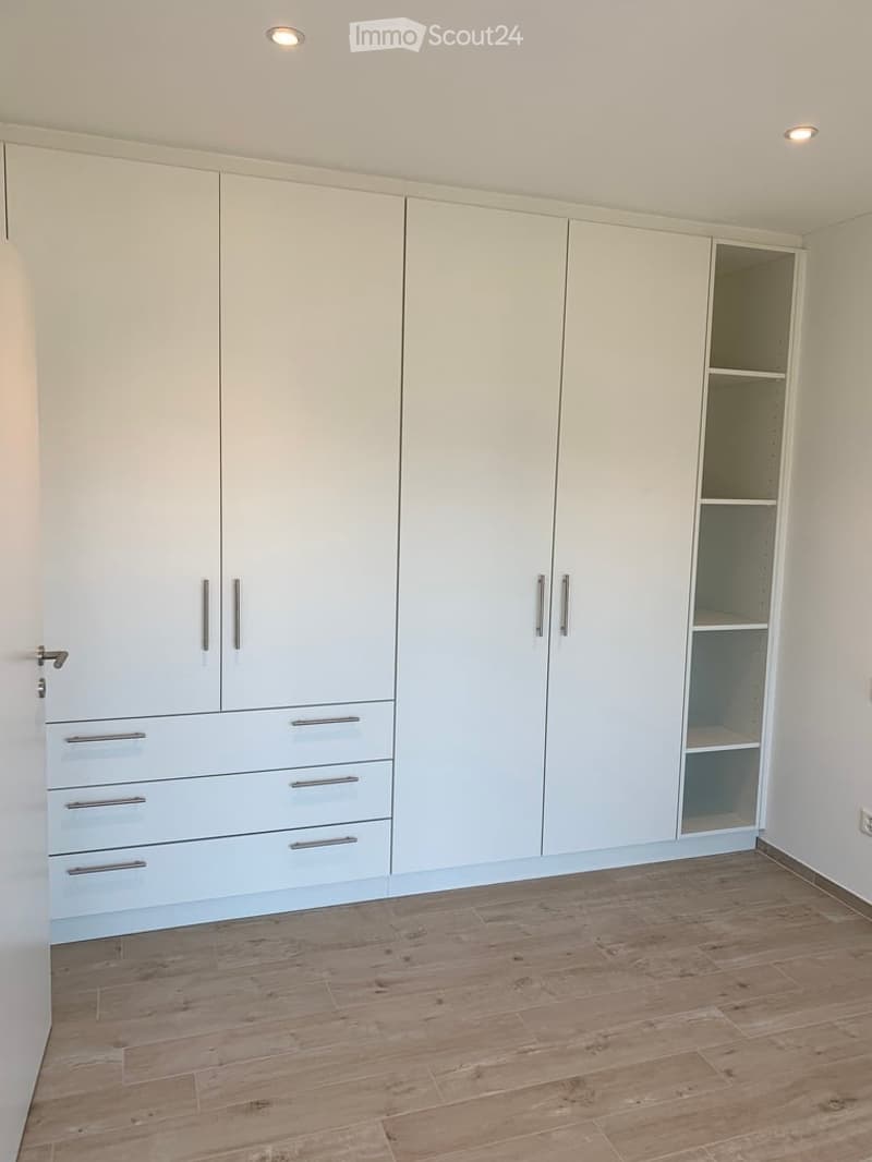 Empty room with light-colored built-in wardrobes and wooden flooring.