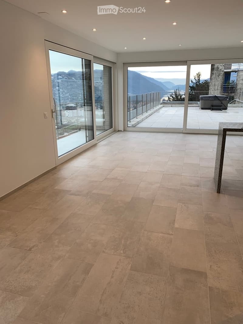 Empty room with large glass doors leading to a balcony, tiled floor, and scenic mountain view.