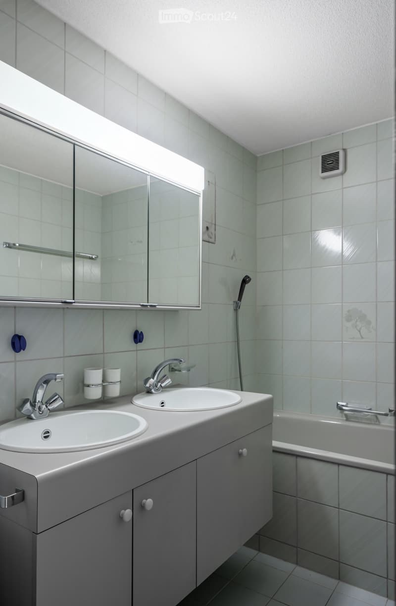Modern bathroom with two sinks, a large mirror, a bathtub, and a showerhead on the wall.