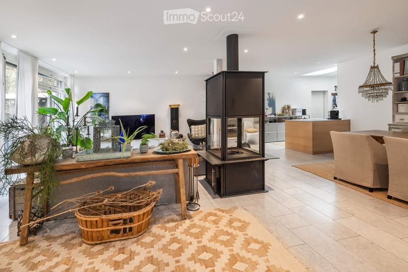 Modern living room with a fireplace, large windows, a sofa, coffee table, dining area, and kitchen island.