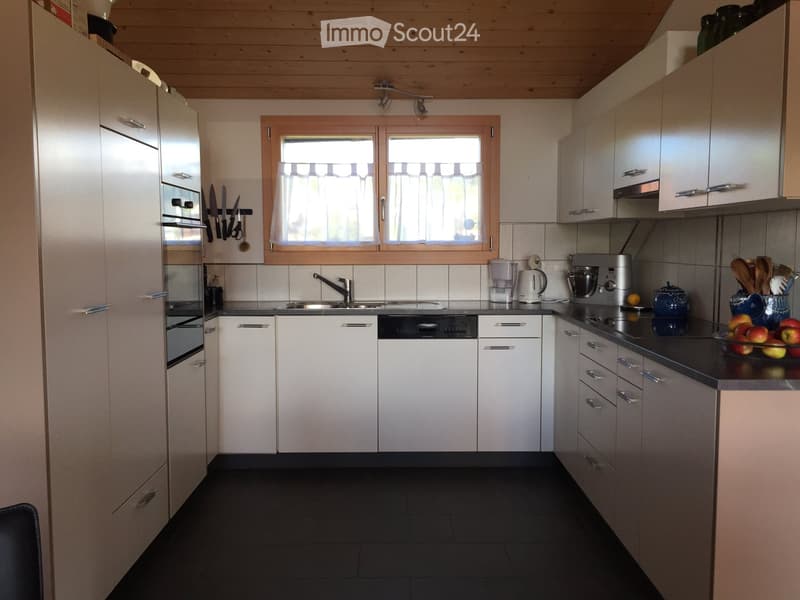 Modern kitchen with white cabinets, stainless steel appliances, and a black countertop. Features include a refrigerator, oven, dishwasher, sink, blender, coffee maker, mixer, and various kitchen utensils.