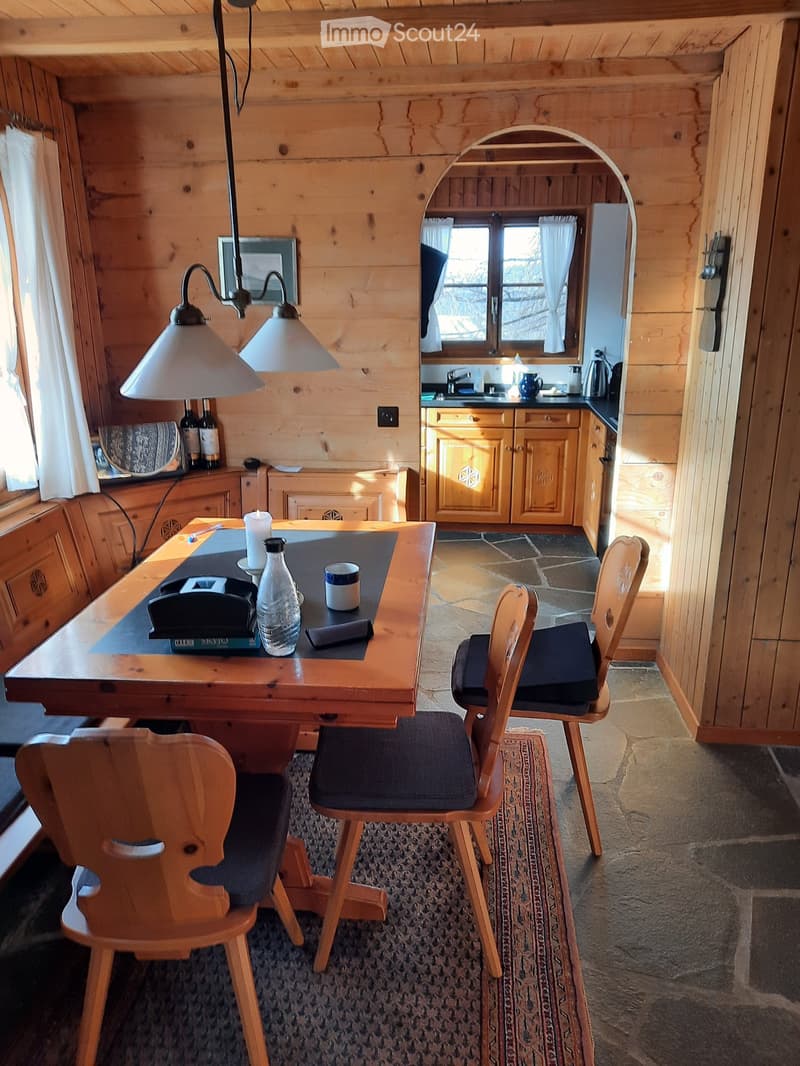 wooden interior, dining table, 4 chairs, candle, bottles, rug
