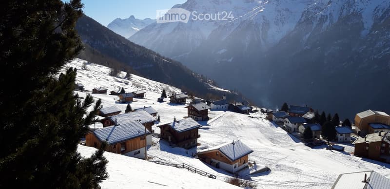 A picturesque village nestled in a snowy mountain valley, with traditional wooden houses and chalets scattered across the landscape.