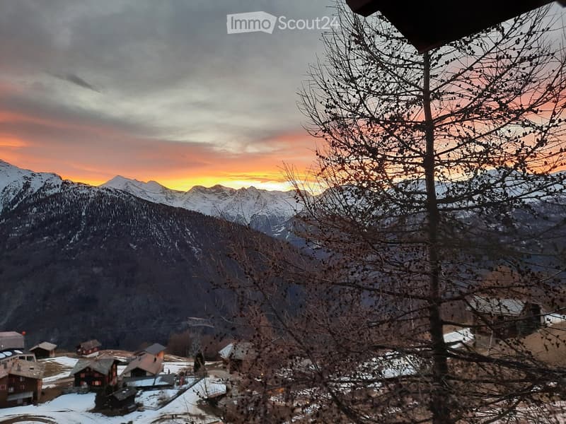 Sunset over mountain range, snowy landscape, village houses, clear sky