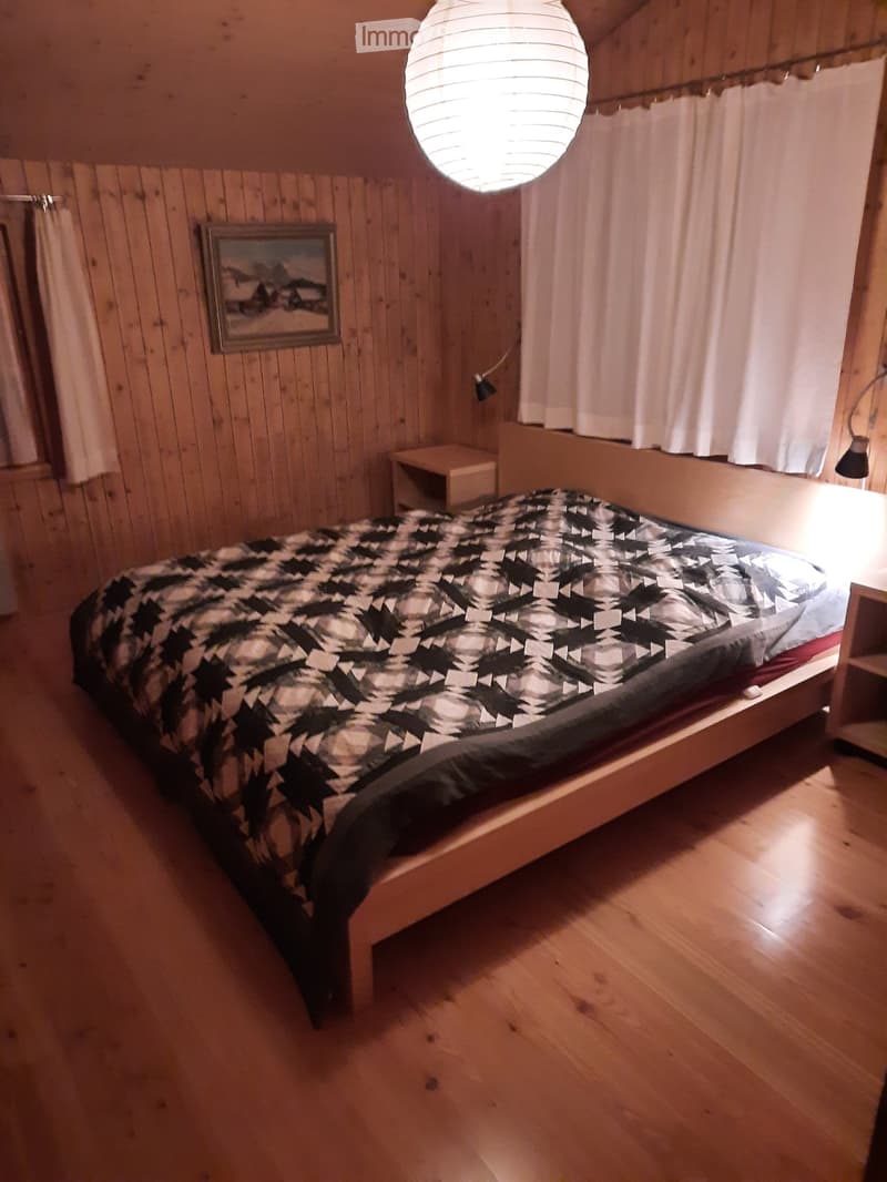 Bedroom with bed, nightstands, curtains, wooden walls, picture frame, lamps