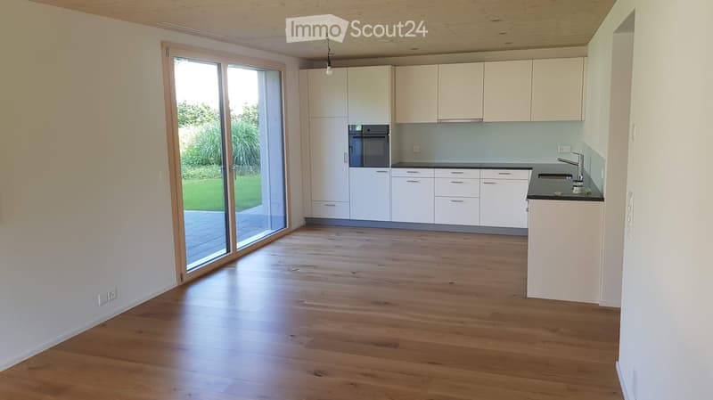 Modern kitchen with white cabinets, wooden flooring, and a large sliding glass door leading to a patio.