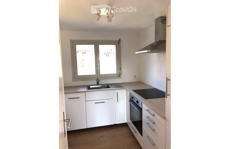 Modern kitchen with white cabinets, stainless steel appliances, and a central island. Features a sink, stove, oven, and range hood.