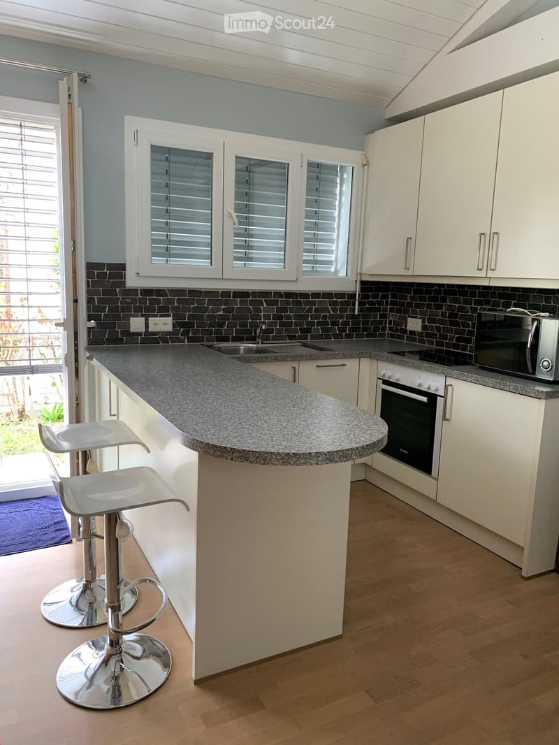 modern kitchen with granite countertops, white cabinets, integrated oven and microwave, two stools at the island