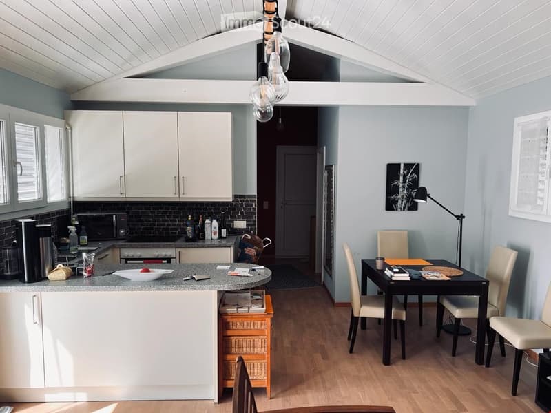 Modern kitchen with breakfast bar, island, granite countertops, stainless steel appliances, white cabinetry, pendant lighting, dining area with dark wood table and chairs.