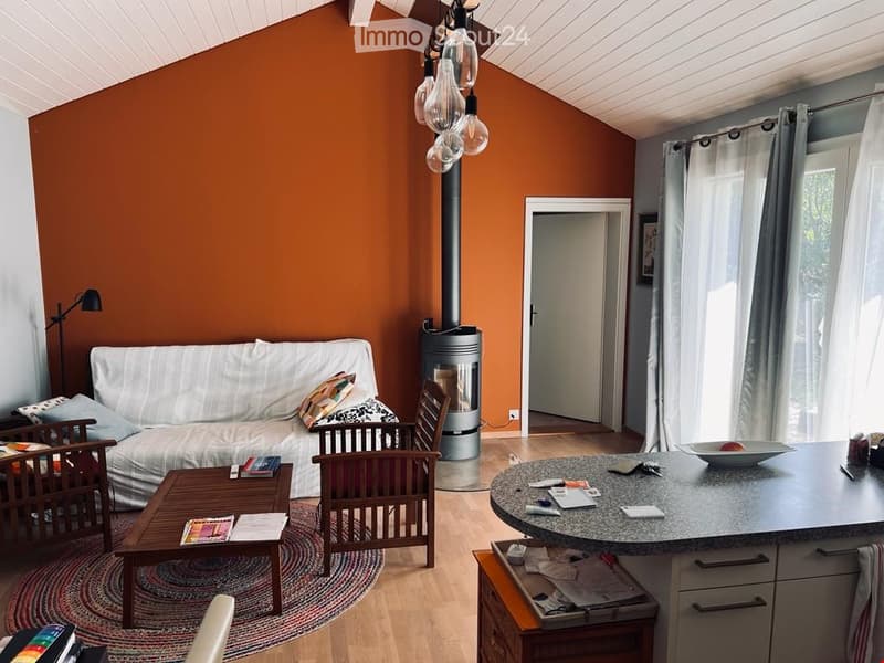 Orange walls, a white sofa with decorative pillows, a round wooden coffee table, a wooden chair, a fireplace, and a black lamp.
