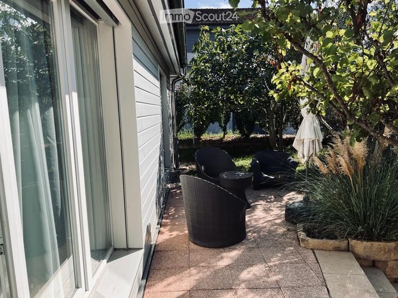 Backyard with black wicker chairs, table, white patio umbrella, plants