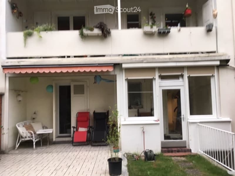 Balcony area with white and red chairs, small table, potted plant, and green grass patch.