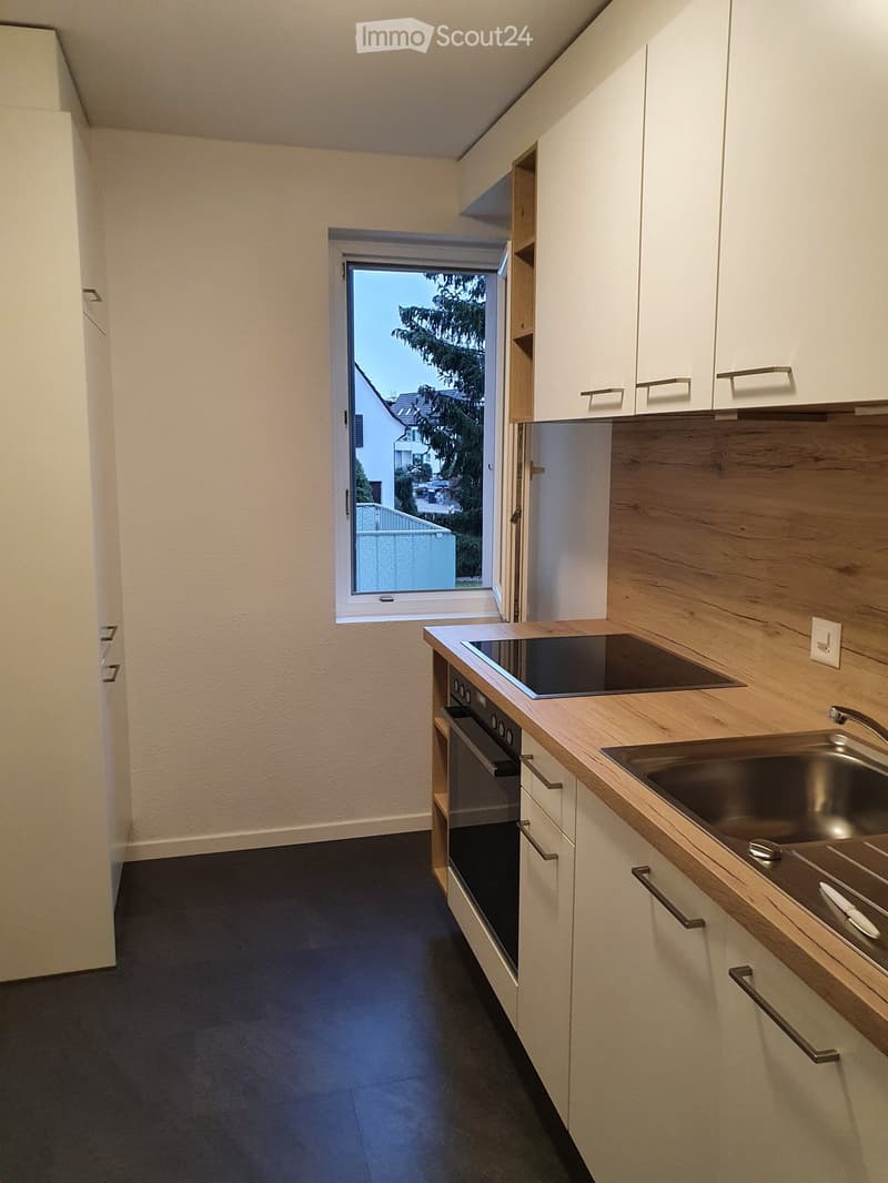Modern kitchen with white cabinets, wooden countertops, stainless steel sink, and built-in oven and stove. Features a window with a view of the outside.
