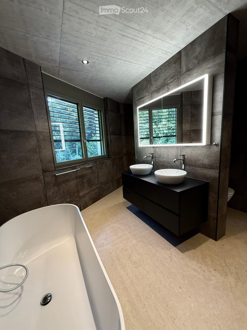 Modern bathroom with a large bathtub, double sink vanity, sleek mirrors, and contemporary fixtures.
