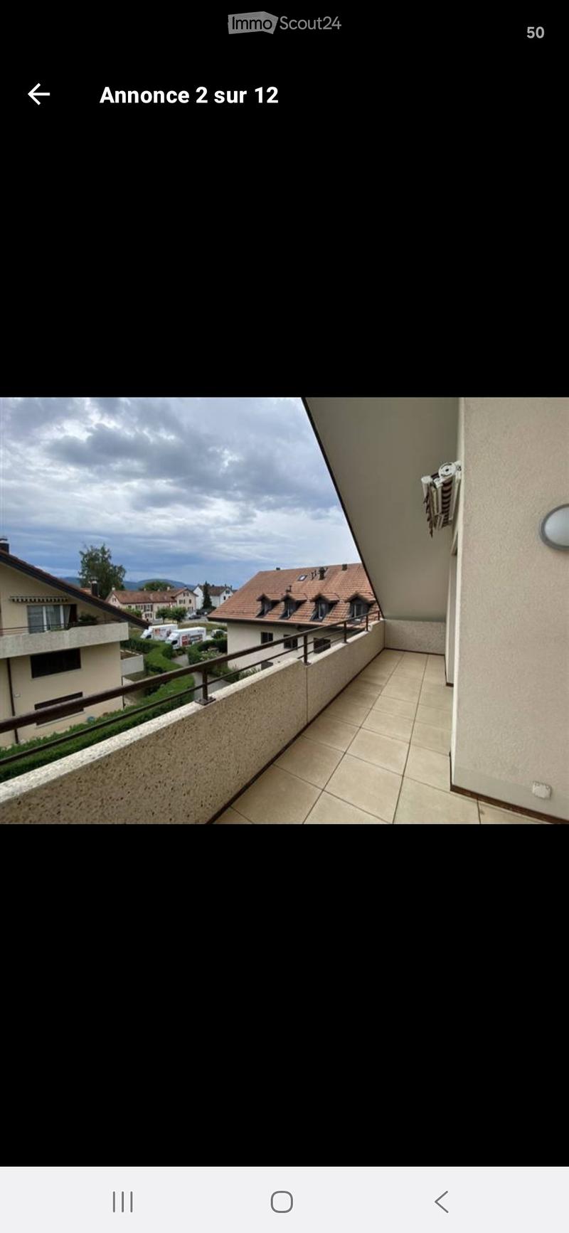 Balcony with tiled floor, metal railing, and view of neighboring houses and landscape.