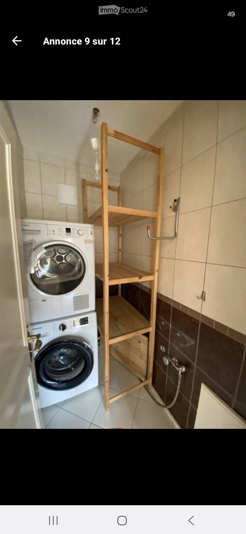 Bathroom with a washing machine, wooden shelf, tiled walls, and a shower area.